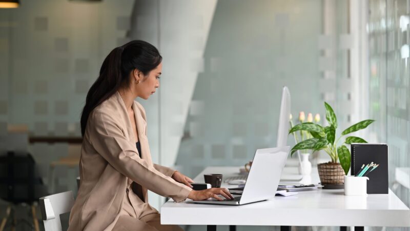 Side view of young professional female manager working on laptop